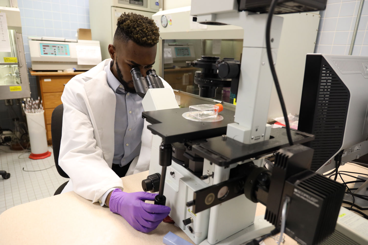 A young student scientist looking into a microscope.