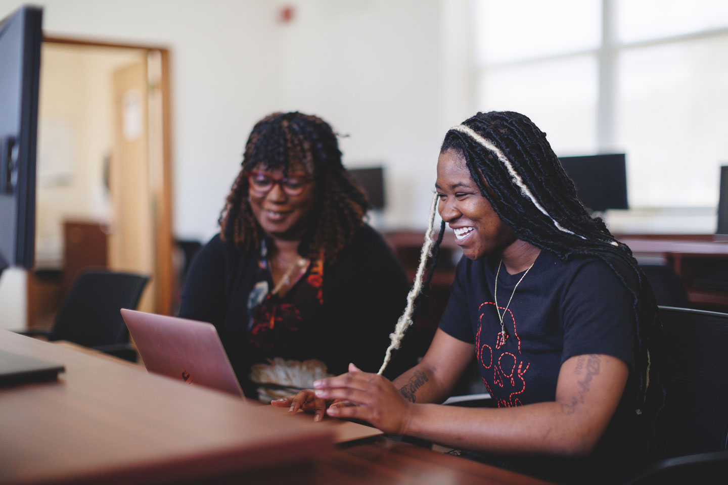 A pair of female students smiling and doing school work.