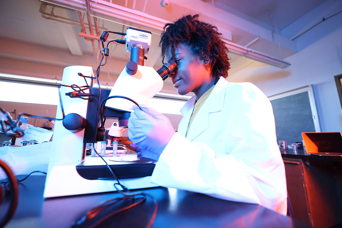 A student scientist looking into a microscope.