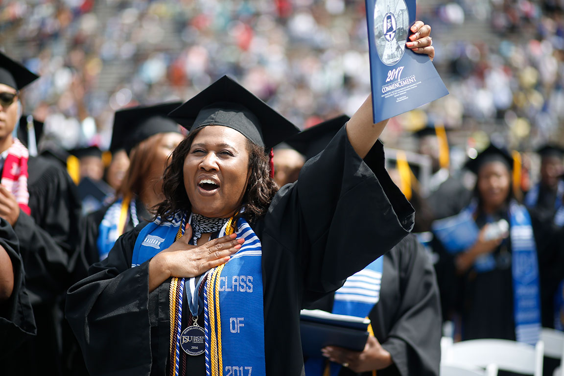 A young woman celebrating during an outdoor graduation.