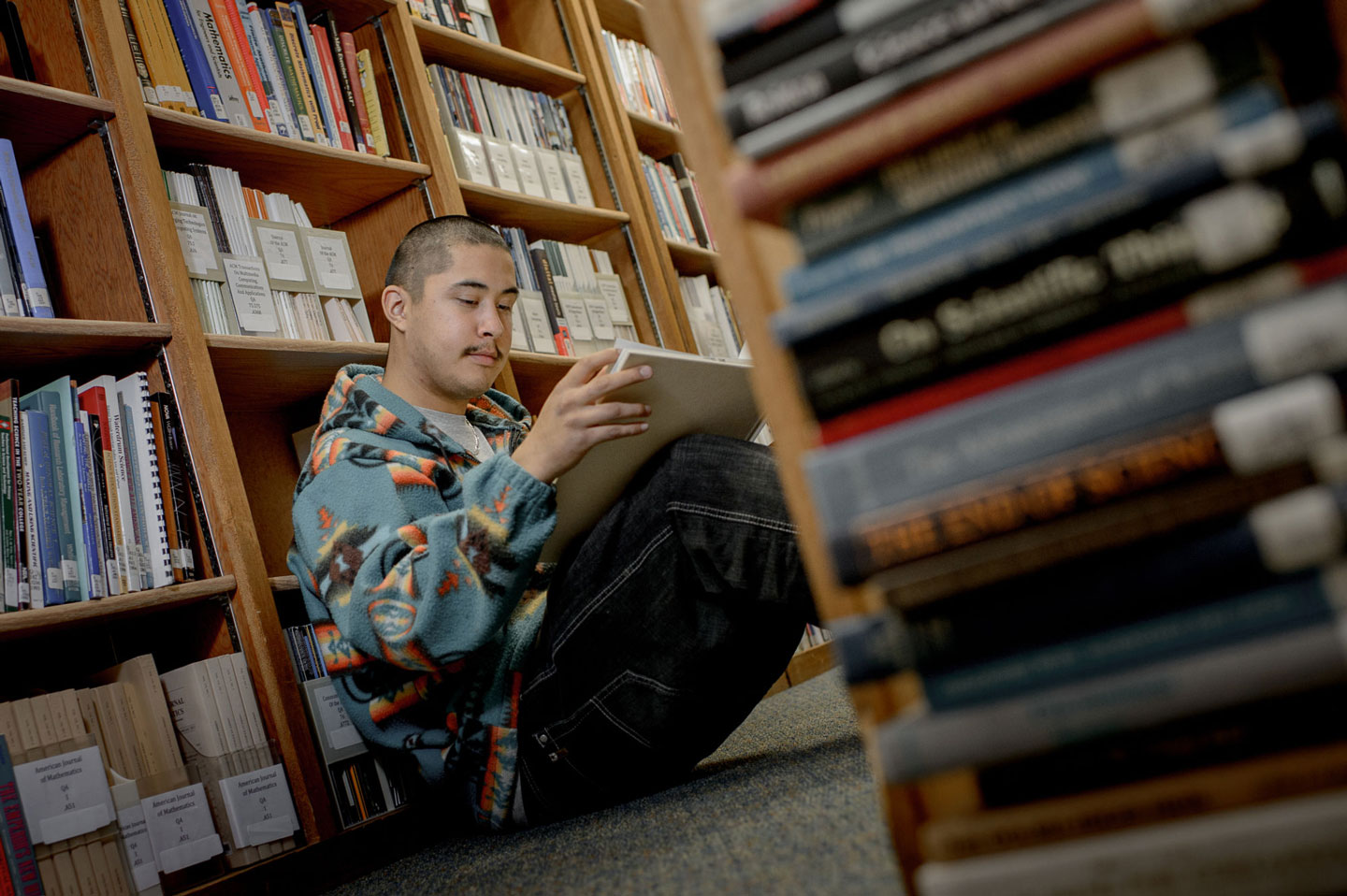 A student reading a book in a school library.
