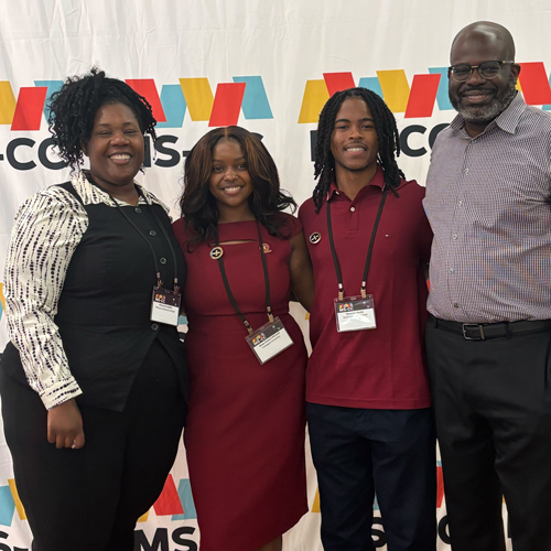 Two students posing with two mentors at an event.