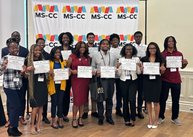 Fourteen MS-CC summer intern students taking a group photo with their certificates.